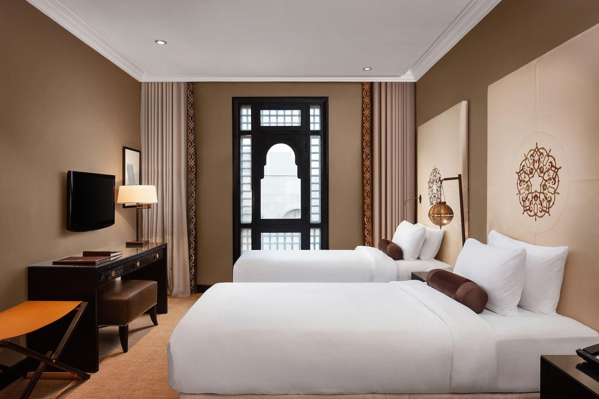 샤자 마디나 호텔 메디나 외부 사진 The photo shows a well-decorated hotel room featuring two single beds with white bedding. The walls are a warm beige color, and there are decorative elements such as patterned wall panels and a large window with an elegant design. In the room, there 