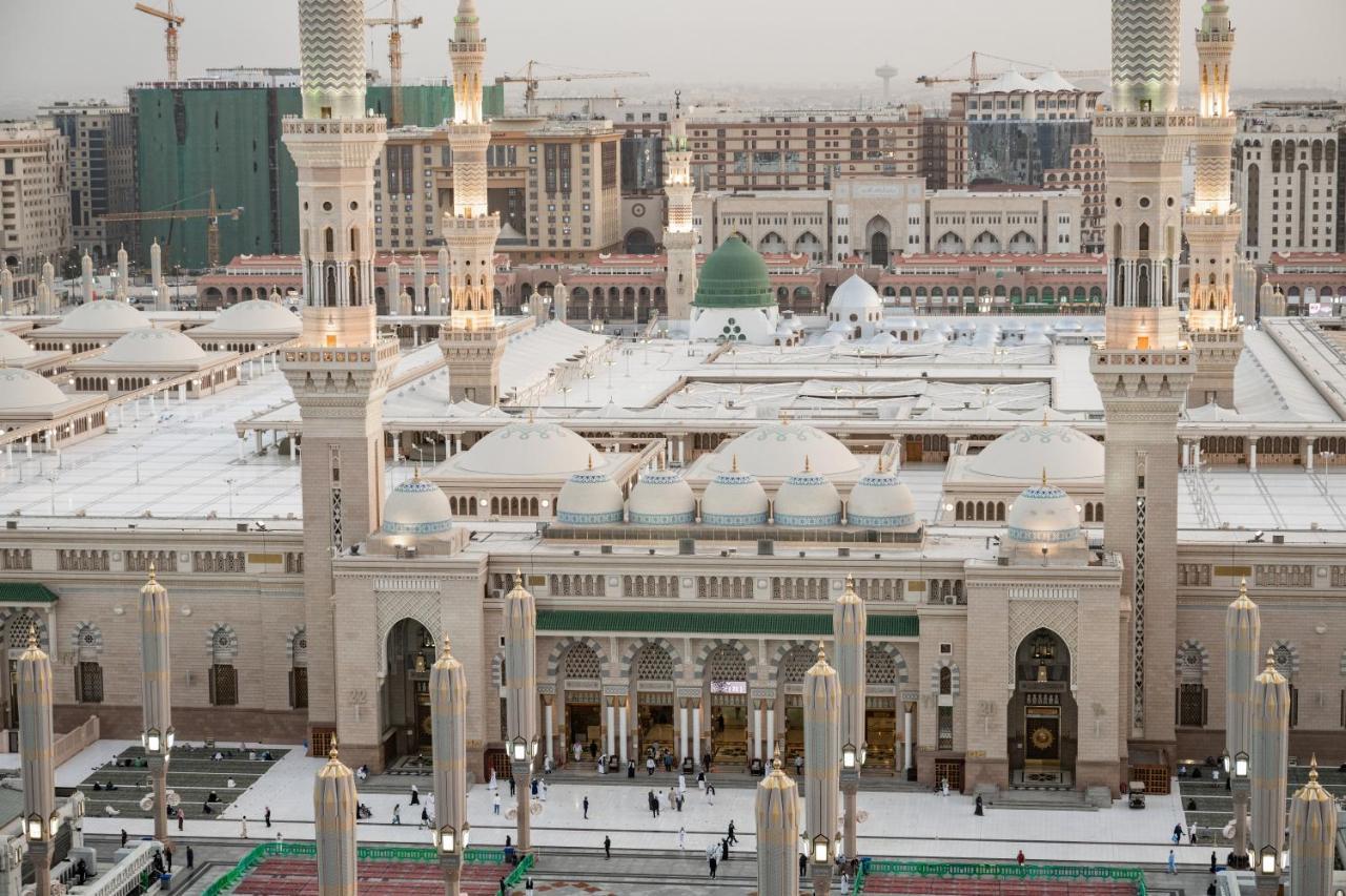 샤자 마디나 호텔 메디나 외부 사진 The photo shows an aerial view of a mosque complex, with prominent architectural features such as tall minarets and a large dome. The structure is notable for its intricate design and is likely surrounded by an open courtyard where people are gathere
