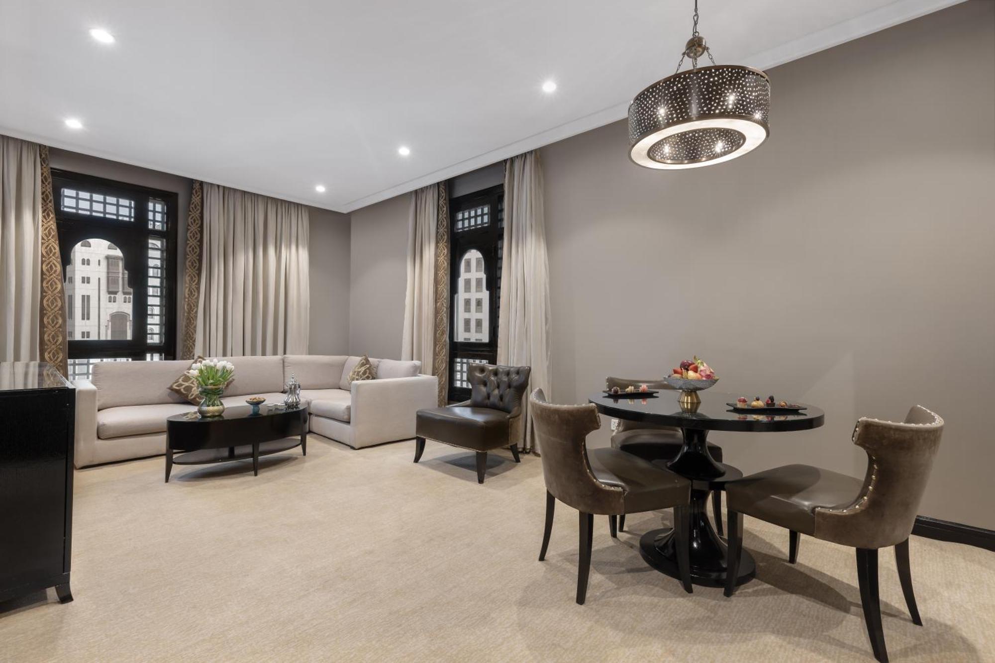 샤자 마디나 호텔 메디나 외부 사진 The photo showcases a modern and elegantly designed living space. It features a light-colored sofa arranged against a wall, complemented by a round dining table with stylish chairs. A small coffee table sits in front of the sofa, and there's a decora