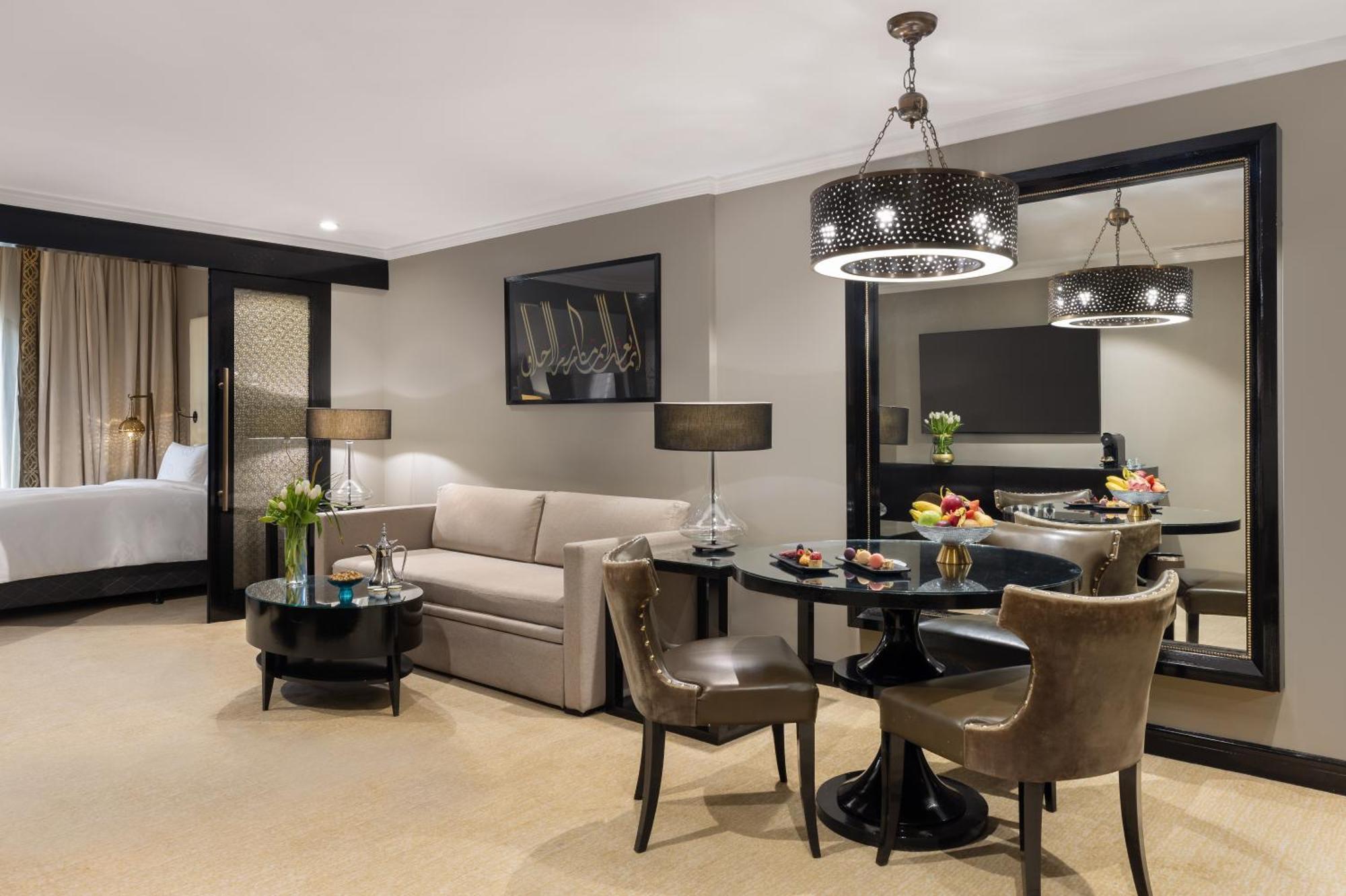 샤자 마디나 호텔 메디나 외부 사진 The photo shows a stylish hotel or apartment room designed for comfort and elegance. 

- On the left, there's a light-colored sofa paired with a round coffee table.
- Adjacent to the sofa, there are two upholstered chairs, creating a cozy seating are