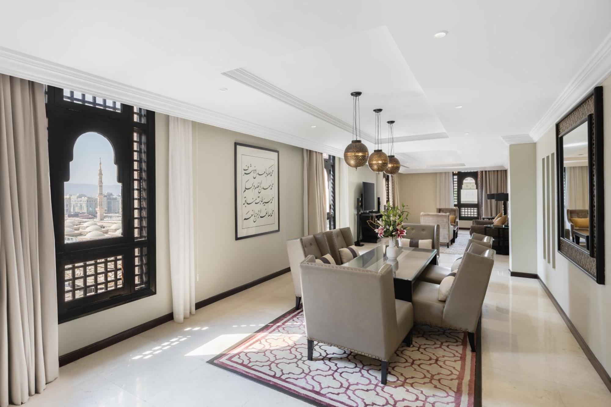 샤자 마디나 호텔 메디나 외부 사진 The photo shows a spacious and elegantly designed interior of a living or dining area. The room features a long table surrounded by several plush chairs, suggesting a space for dining or gatherings. 

Large, ornate windows allow natural light to floo